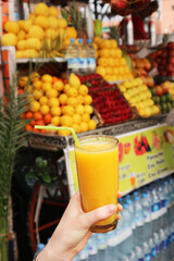 Tourist holds a glass of fresh juice in Jemaa el-Fnaa Square. Marrakesh, Morocco.