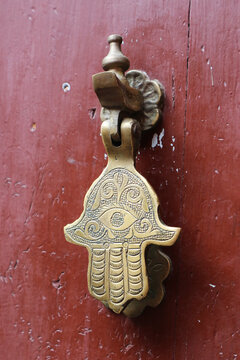 Door knocker in shape of hand of fatima. Hamsa doorknob on wooden door.