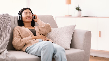 Obraz premium Asian woman listening to music wearing wireless headphones