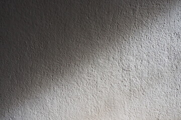 Closeup of warm sunlight shining on rough cement wall with texture and rough surface in the dark room for background and decoration