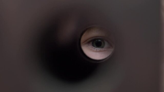 The boy looks into the binoculars with one eye