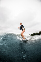 happy young athletic woman riding the river wave and showing hand gesture