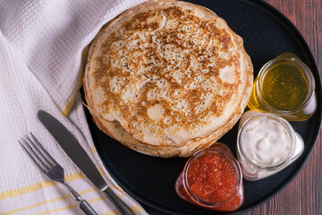 Pancakes on a plate and red caviar,honey and cream.