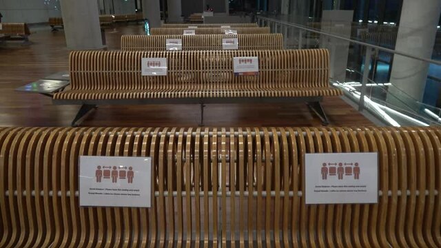 Dalaman Airport, Antalya, Turkey - 2nd of September 2020: 4K Empty benches with social marking notice in the night airport

