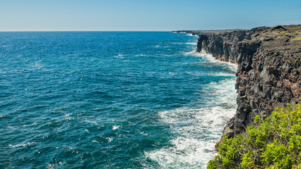 Fototapeta na wymiar Cliffs on the seashore. Large boulder among the waves in the sea. Hawaii