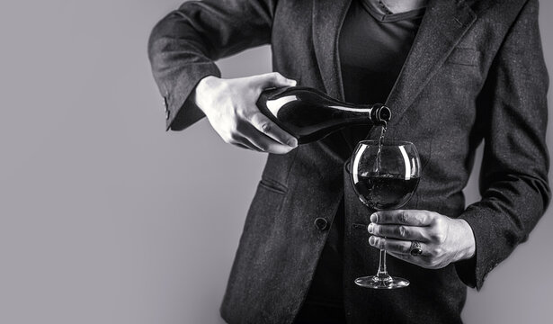 Gourmet drink bottle, red wine glass, sommelier, tasting. Waiter pouring red wine in a glass. Sommelier man, degustation, winery, male winemaker. Red wine is poured from bottle to glass.