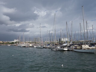 Fototapeta na wymiar BARCELONA, SPAIN on SEPTEMBER 2019: View to yachts in port of european city at Catalonia district, cloudy sky in cold summer day.