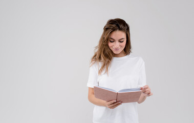 Image of beautiful brunettewoman wearing white t-shirt making notes in diary book isolated over white background