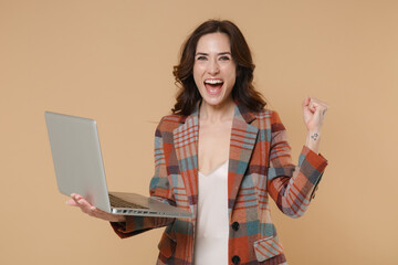 Happy young brunette woman 20s wearing casual checkered jacket posing standing holding working on...