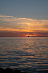 A man standing on a surf board on the calm bay water with the nuclear power plant Barsebäck...