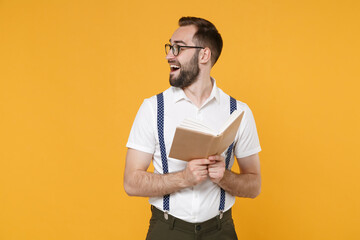 Excited young bearded man 20s wearing white shirt suspender eyeglasses posing standing holding in...
