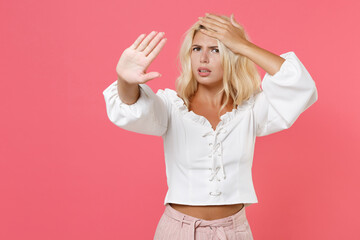 Puzzled displeased young blonde woman 20s in white casual clothes standing showing stop gesture...