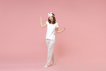 Full length portrait overjoyed young woman in white pajamas home wear sleep mask clenching fists...