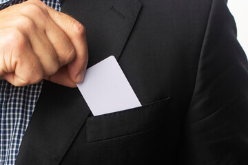 The businessman takes a white business card out of his jacket pocket.