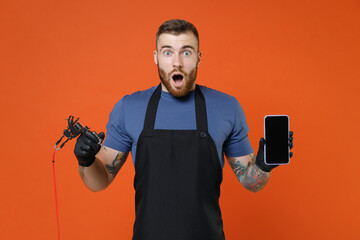 Shocked professional tattooer master artist man in t-shirt apron hold machine black ink jar...