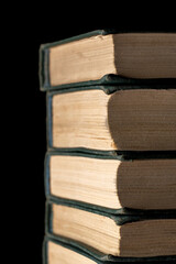 A stack of old books on a black background.