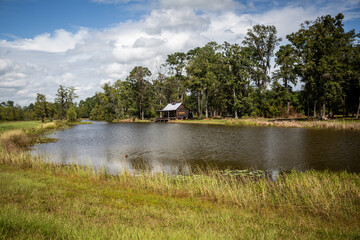 Scenic view of the exterior of a rural rustic wooden camp house used for fishing and hunting. The house is located on a large pond