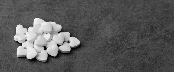 Fototapeta na wymiar White medical pills in the form of hearts on a gray background.