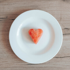 Fototapeta na wymiar Ripe watermelon heart slice on a white plate on the table