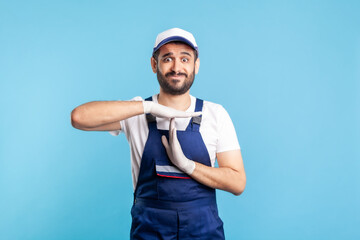 Overworked handyman in overalls and gloves showing time out gesture, need break. Profession of...