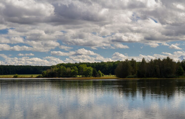Obraz na płótnie Canvas Pond water shore with tree meadow, dry grass and cloud sky. Czech landscape