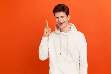 Cheerful young man pointing finger up and sincerely laughing, miscievous teenager thinking devious...