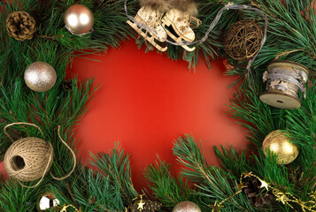 Golden Christmas toys and pine branches on a red background, top view. The concept of the new year 2021 and Christmas.