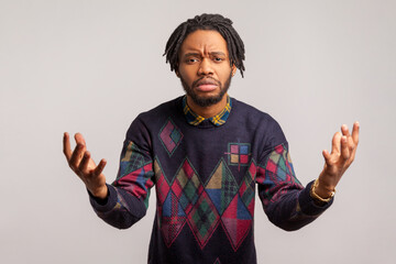 Worried exhausted african man with dreadlock spreading hands asking what, tired irritated of questions, misunderstanding. Indoor studio shot isolated on gray background