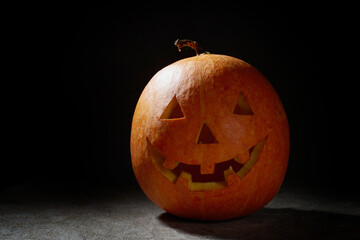 Halloween pumpkin smile and scary eyes for party night. Close up view of scary Halloween pumpkin with eyes glowing inside at black background. Selective focus
