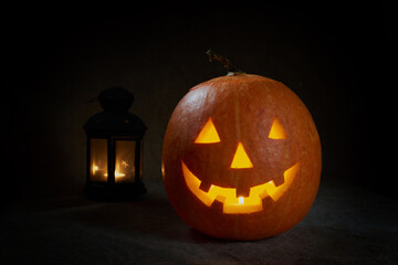 Halloween pumpkin smile and scary eyes for party night. Close up view of scary Halloween pumpkin with eyes glowing inside at black background. Selective focus