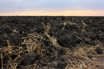 Sunset over plowed field. Countryside landscape with plowed land after harvest in autumn. 