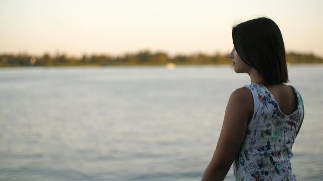 Beautiful girl standing on Dnipro river bank on sunny day in summer in slo-mo 