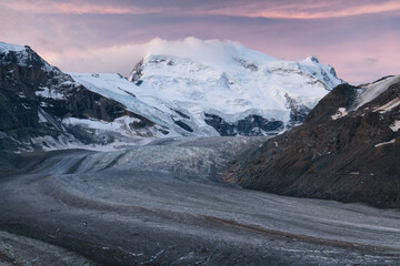 Swiss mountain Grand Combin during blue hour with purple sky, calm white couds, glacier, rocks