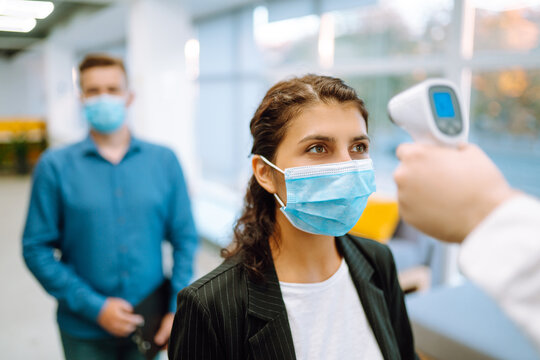 Disease Control Experts Use An Infrared Thermometer Equipment To Check The Temperature On The Forehead Before Entering At Office. Сhecking The Temperature Of Office Workers. Covid-19.