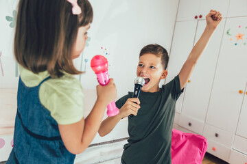 Family at home. Portrait of a happy children singing karaoke through microphone at home.