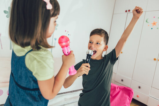 Family At Home. Portrait Of A Happy Children Singing Karaoke Through Microphone At Home.