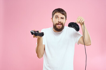 Fototapeta na wymiar Man with two joysticks in hands fun game technology lifestyle pink background
