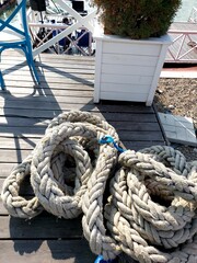 Fototapeta premium Wooden furniture on the cafe veranda and mooring rope. The sailing competition. Veranda with water view .