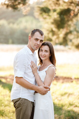 beautiful young couple are hugging in the summer park. stylish man and woman having fun outdoors. family day concept. copy space.