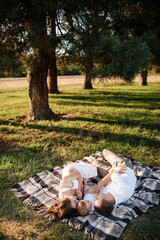Mom, dad and little son lying on the blanket in the summer park. The concept of summer holiday. Mother's, father's, baby's day. Family spending time together on nature. Family look