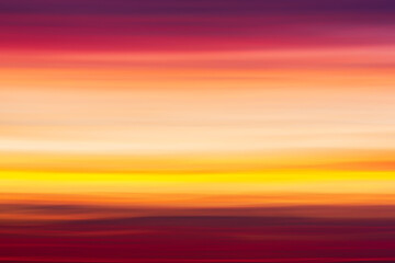 Vibrant colorful striped background of red, pink, purple and orange clouds in blurry sunset sky