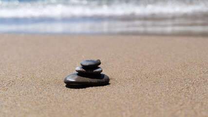 Fototapeta na wymiar Stone meditation on sand beach. Balance stones near the sea. Concept of harmony, stability, life balance, relaxation