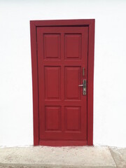 A wooden door painted red against a white wall.