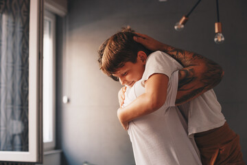 The father holds his son in his arms, they are in the living room, the family moments