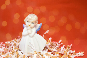 on the tinsel is a statuette in the form of an angel on a red background.