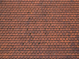 Tiled roof in Europe, Germany. Travel picturesque background and texture photo. Detailed view of wet old red roof shingles. Colorful photo