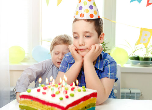 Two beautiful children boys blowing candles on homemade baked cake