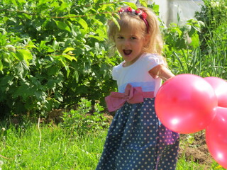 little child playing with red air balloons