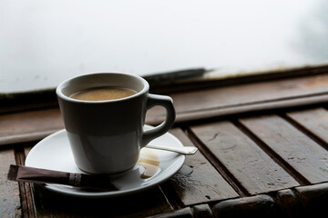 A cup of coffee and brown sugar on wooden shelf