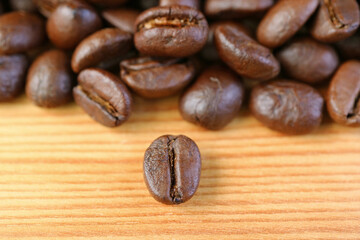 Closeup a Robusta Roasted Coffee Bean with Blurry Coffee Beans Pile in the Backdrop